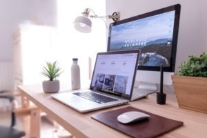 A laptop with a website on the screen with another screen behind it, representing website maintenance.