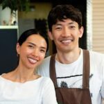 Smiling small business owners standing together inside their shop