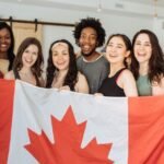Group of smiling Canadian business owners holding a Canadian flag, representing starting and registering a business in Manitoba.