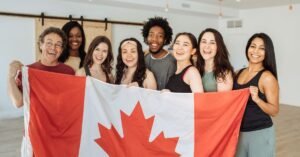 Group of smiling Canadian business owners holding a Canadian flag, representing starting and registering a business in Manitoba.